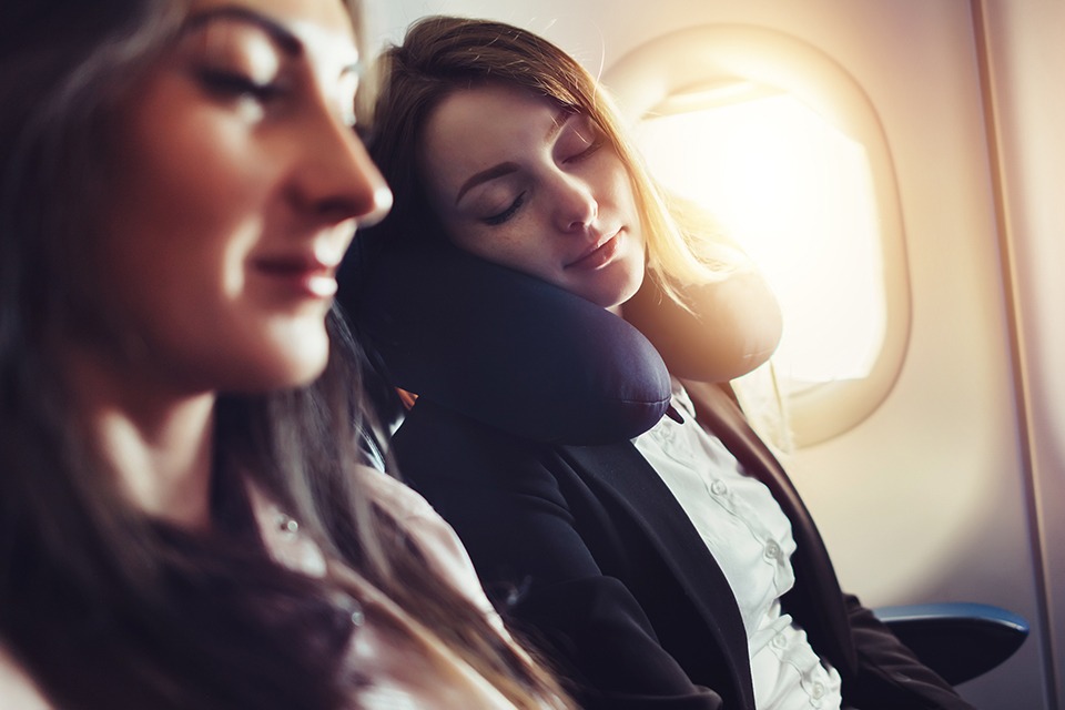 femme dormant dans un avion avec des protections auditives