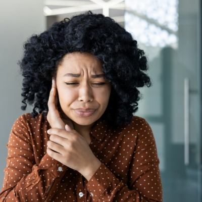 Femme se couvrant une oreille en fronçant les sourcils