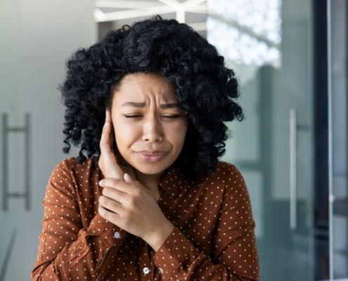 Femme se couvrant une oreille en fronçant les sourcils