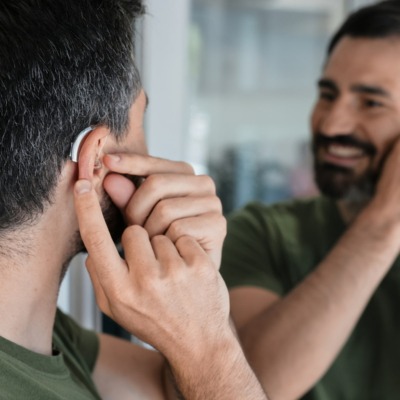 Homme mettant en place son appareil auditif